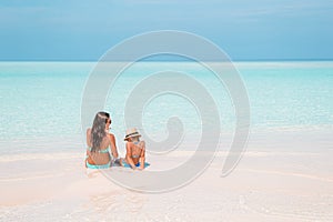 Beautiful mother and daughter at Caribbean beach enjoying summer vacation.