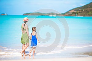 Beautiful mother and daughter at Caribbean beach enjoying summer vacation. Family walking on tropical famous Jolly bay