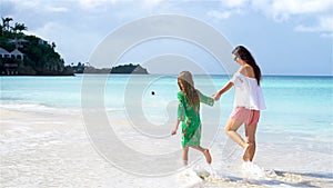 Beautiful mother and daughter on Caribbean beach. Family walking on tropical seashore. SLOW MOTION