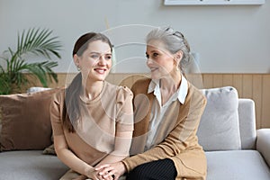 Beautiful mother and daughter. Cheerful young woman is embracing her middle aged mother in living room. Family portrait