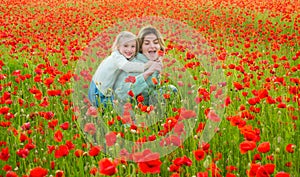 Beautiful mother and daughter in spring poppy flower field. Mom holds her child daughter in the flowering meadow