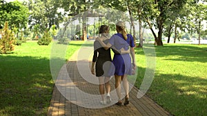 Beautiful mother and daughter walking along park enjoying pastime outdoor