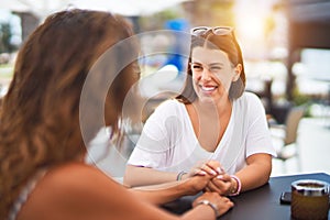 Beautiful mother and daugther sitting at terrace of a restaurant speaking and smiling