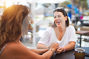 Beautiful mother and daugther sitting at terrace of a restaurant speaking and smiling