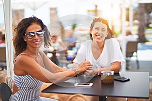 Beautiful mother and daugther sitting at terrace of a restaurant speaking and smiling