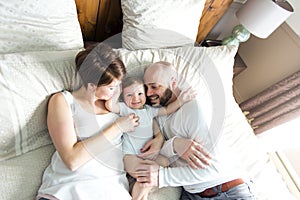 Beautiful mother and handsome father with baby daughter lying on bedroom