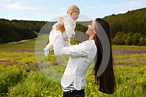 Beautiful mother having fun with her little cute baby in summer garden