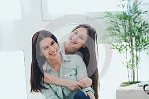 Beautiful mother and her cute daughter smiling and posing at home.