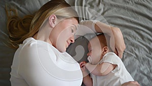 Beautiful mother and her cute little baby are sleeping at home,hugging in bed. Child safety and protection, co-sleeping