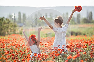 Beautiful mother and her daughter playing in spring flower field