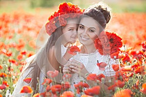 Beautiful mother and her daughter playing in spring flower field