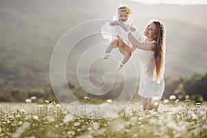 Beautiful mother and her daughter playing in spring flower field