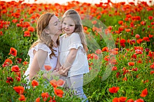 Beautiful mother and her daughter in spring poppy flower field, Czech republic