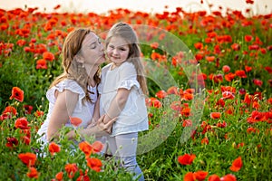 Beautiful mother and her daughter in spring poppy flower field, Czech republic