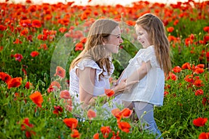 Beautiful mother and her daughter in spring poppy flower field, Czech republic