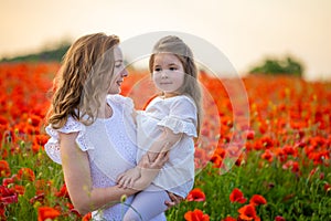 Beautiful mother and her daughter in spring poppy flower field, Czech republic