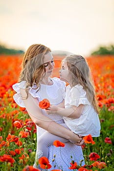 Beautiful mother and her daughter in spring poppy flower field, Czech republic