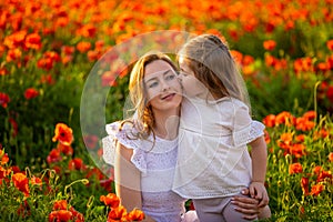 Beautiful mother and her daughter in spring poppy flower field, Czech republic