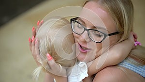 Beautiful Mother And her little daughter indoors. Kissing and hugging happy family. Happy Mother`s Day Joy. Mom and Baby