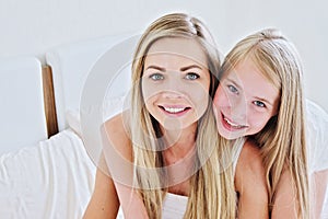 Beautiful mother and her pretty daughter teenager smiling at home