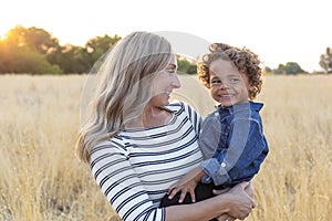 Beautiful Mother holding her adorable curly haired son in the outdoor sunlight