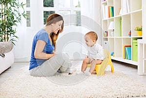 Beautiful mother learning little child how to sitting on potty