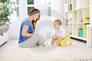 Beautiful mother learning little child how to sitting on potty photo