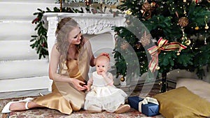 A beautiful mother with a little daughter in her arms decorates the Christmas tree in the living room. New Year's