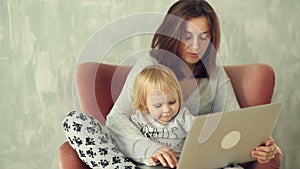 Beautiful mother with little daughter using laptop