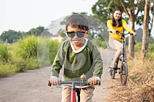 A beautiful mother playing a bicycle with her son