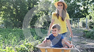 Beautiful mother playing and having fun with his son with a wheelbarrow in the mountain.