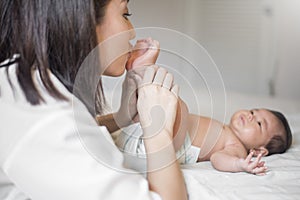 Beautiful mother is playing with her newborn baby in the bedroom