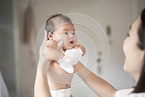 Beautiful mother is playing with her newborn baby in the bedroom