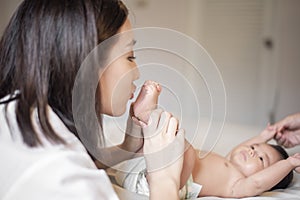 Beautiful mother is playing with her newborn baby in the bedroom