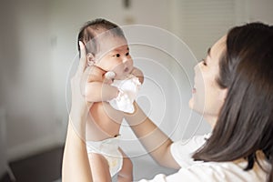 Beautiful mother is playing with her newborn baby in the bedroom