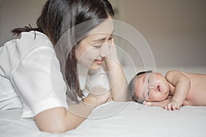 Beautiful mother is playing with her newborn baby in the bedroom