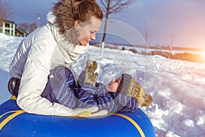 Beautiful mother plays with her child, a boy of 4 years. In the winter in the fresh air. Background of snow and drifts