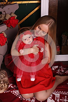 Beautiful mother posing with her cute little baby girl beside Christmas tree