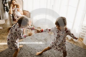 Beautiful mother sits in the armchair with her little baby next to the fireplace and New Year`s tree with gifts in the