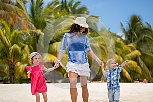 Beautiful mother, son and daughter walking on the beach of the Indian ocean.