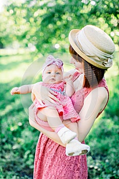 Beautiful Mother with the straw hat And her little daughter outdoors family look in in a pink dress . Outdoor Portrait