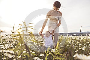 Beautiful mother is walking on field with little baby boy