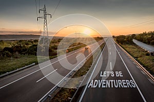 Beautiful Motorway with a Single Car at sunset with motivational message Let`s Be Adventurers