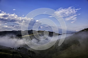 Beautiful mountain landscape of a foggy morning with trees and clouds