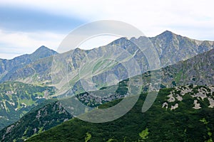 Beautiful mountain landscape with green grass on blue sky background