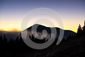 Beautiful mountain landscape with hazy peaks and foggy valley at sunset