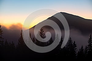 Beautiful mountain landscape with hazy peaks and foggy wooded valley at sunset