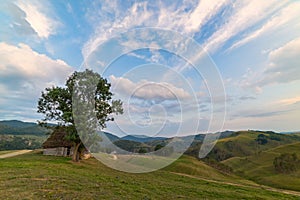 Beautiful mountain landscape with and old house, trees and a cloudy morning sky