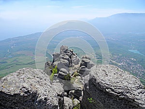 Beautiful mountain landscape with rounded rocks. Top view of the inhabited valley with lake. Distant mountain plateaus in a blue