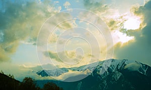 Beautiful mountain landscape: sky, clouds, sun and snow-capped mountains